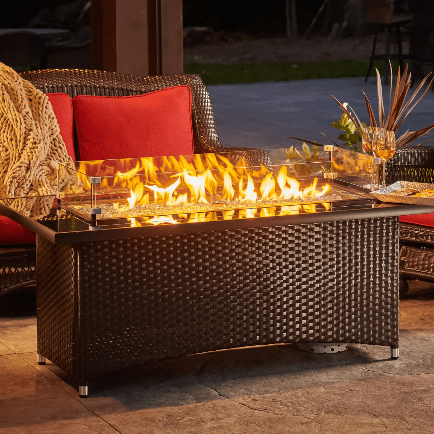 Wicker patio chairs with red cushions surrounding a modern fire pit table, a top choice for Patio Furniture near me.